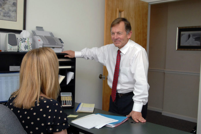 PLANNING AHEAD: Entwistle Financial Life Planning founder Bill Entwistle says the elderly are susceptible to scams because of their age and their accumulated assets. Above, he speaks with paraplanner Terry Hazel in his South Kingstown office. / PBN PHOTO/BRIAN MCDONALD