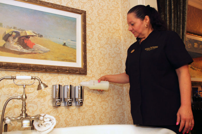 SEAL OF APPROVAL: Odena Chacon, room attendant at the the Hotel Viking, fills shampoo dispensers. The hotel uses cleaning chemicals that are “Green Seal” certified. / PBN PHOTO/KATE WHITNEY LUCEY