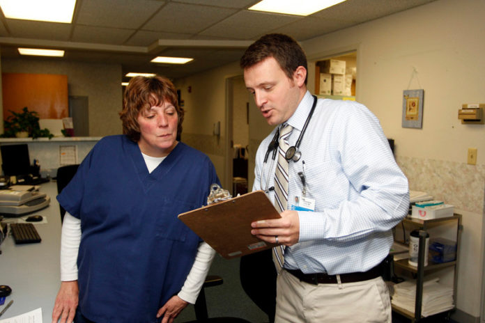 LIFE LINE: Dr. Christopher Furey, pictured above speaking to medical receptionist Ruthie Straight, is utilizing the Primary Care Educational Loan Repayment Program, which is offered by The Rhode Island Foundation. / COURTESY STEW MILNE