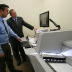 BRASS TAX: The R.I. Division of Taxation&rsquo;s new imaging machine operated by state Tax Administrator David Sullivan, right, and Daniel Clemence, the division&rsquo;s chief revenue agent and head of e-government efforts. / PBN PHOTO/MICHAEL PERSSON