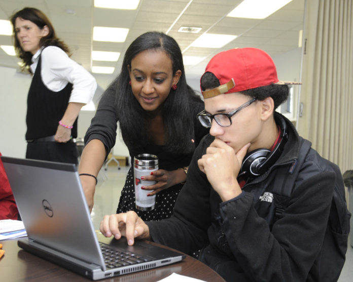 TECH SUPPORT: Science teacher Malika Al works with student Joshua Estrada at the Sheila C. “Skip” Nowell Leadership Academy, which opened its doors on Sept. 16. / PBN PHOTO/MARTIN GAVIN