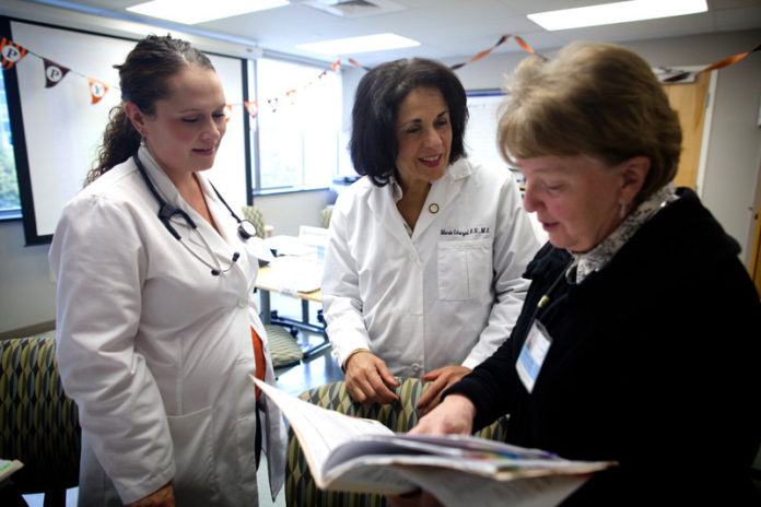 A CARING SPIRIT: Thanks to volunteers like student nurse Marissa Roberge, left, and nurse practitioner Rebedda Carley, right, Rhode Island Free Clinic CEO Marie Ghazal has been able to expand the number of clinic visits 400 percent since 2008. / PBN PHOTO/STEPHANIE ALVAREZ EWENS