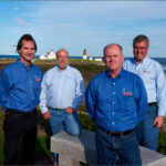 BUILT FROM SCRATCH: SkillBuilders executives, left to right, John Watson, director of Oracle Database Services; Bob Benoit, Internet architect; Dave Anderson, president; and Gary Belke, director of business operations, take a break at Point Judith Light in Narragansett in May, during an annual meeting to review projects for European customers. / COURTESY MIKE LAPTEW
