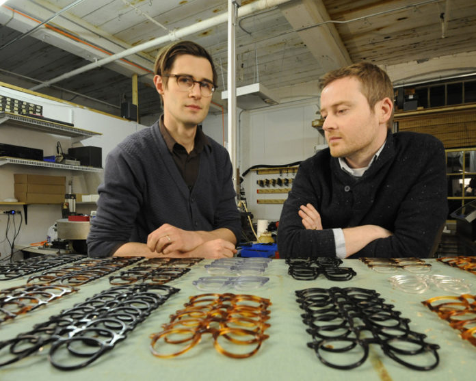 SEEING CLEAR: Lee Allen Eyewear co-owners Lee Kuczewski, left, and Declan Haplin pose with some of their eyeglass frames. In addition to made-to-order, custom frames, Lee Allen also makes limited-edition designs sold at high-end shops. / PBN PHOTO/MARTIN GAVIN