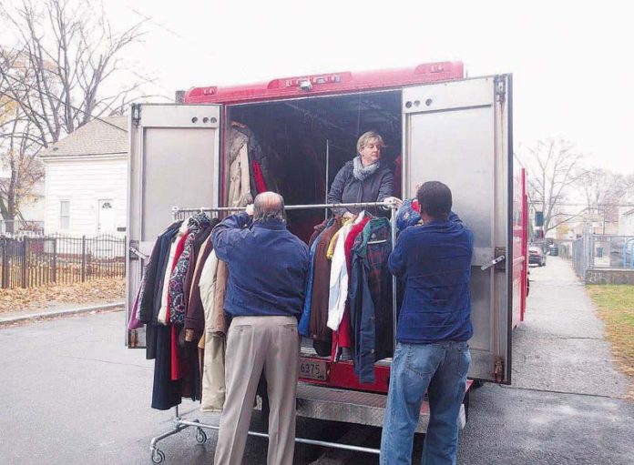 LYNN WILLIAMS, owner of Seven Stars Bakery, center, helps Ed Ricci, vice president of sales for Courtesy Cleaners, left, and Kyle Dennis, senior program manager at the South Side Clubhouse, right, unload some of the more than 400 coats collected through the sixth annual drive.