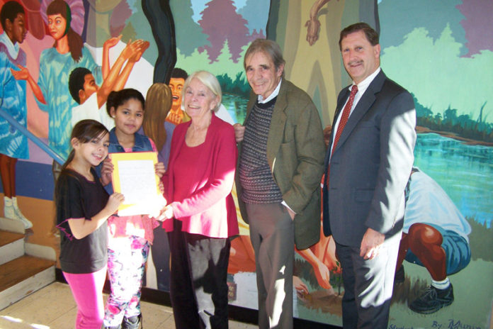 FROM LEFT: Providence third-graders Natalia Bianchi and Keila Quinones hand thank-you cards to Letitia and John Carter and Rhode Island Foundation CEO Neil Steinberg after a press conference announcing the inaugural round of Spark Grants on Dec. 19. / COURTESY R.I. FOUNDATION