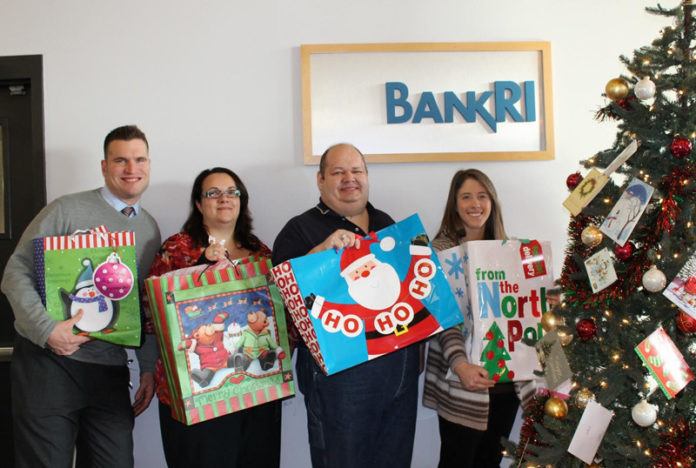 BANK RHODE ISLAND’s customers and staff spread holiday cheer to underprivileged children through area nonprofits. From left: Jeff Elliott, senior banking specialist; Marta Almeida, teller; Keith Dube, donations coordinator for Aids Care Ocean State; and Amanda Flanagan, teller.