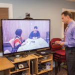 Firms profiting from global office SCREEN TIME: Allied Court Reporters and Video Conference Centers President Jeff Grenier, right, holds a video meeting with company scheduling coordinator Alex Martinez and Human Resources Manager Allison Grenier. The firm credits burdensome travel costs as a driver of videoconferencing. / PBN PHOTO/TRACY JENKINS