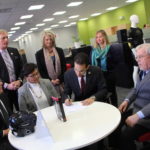 PROVIDENCE MAYOR ANGEL TAVERAS signs a new agreement with the U.S. Small Business Administration to facilitate assistance on a range of topics to enterprises based in the city. Under terms of the previous agreement, which began in May 2012, the SBA, the Center for Women and Enterprise, and SCORE engaged about 150 business owners in 12 workshops. Attending the signing event at Providence's G-form LLC, are, seated from left, Mark S. Hayward, director of the SBA's Rhode Island office, Carmen Diaz-Jusino, program manager for the Center for Women and Enterprise, Taveras, and George Hemond, chair of the Joseph G.E. Knight SCORE chapter. Standing, from left, are James Bennett, Providence director of economic development, Laurie White, president of the Greater Rhode Island Chamber of Commerce, and Meghan Downing, assistant to the CEO at G-Form. / COURTESY PROVIDENCE MAYOR'S OFFICE