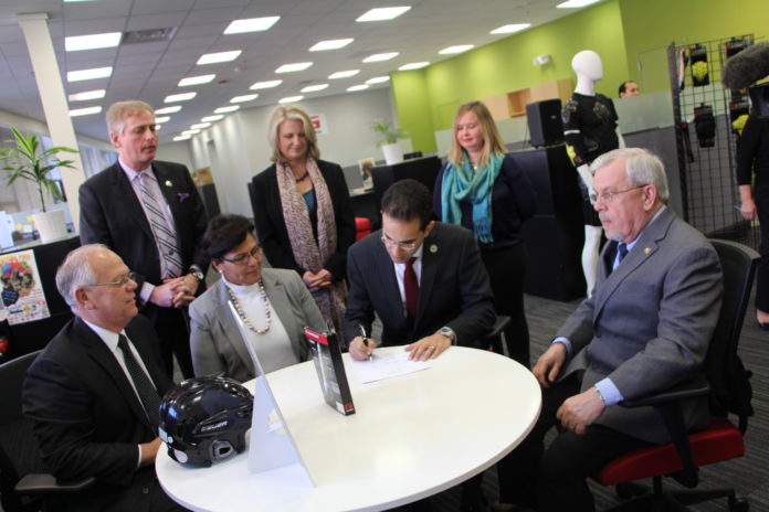 PROVIDENCE MAYOR ANGEL TAVERAS signs a new agreement with the U.S. Small Business Administration to facilitate assistance on a range of topics to enterprises based in the city. Under terms of the previous agreement, which began in May 2012, the SBA, the Center for Women and Enterprise, and SCORE engaged about 150 business owners in 12 workshops. Attending the signing event at Providence's G-form LLC, are, seated from left, Mark S. Hayward, director of the SBA's Rhode Island office, Carmen Diaz-Jusino, program manager for the Center for Women and Enterprise, Taveras, and George Hemond, chair of the Joseph G.E. Knight SCORE chapter. Standing, from left, are James Bennett, Providence director of economic development, Laurie White, president of the Greater Rhode Island Chamber of Commerce, and Meghan Downing, assistant to the CEO at G-Form. / COURTESY PROVIDENCE MAYOR'S OFFICE