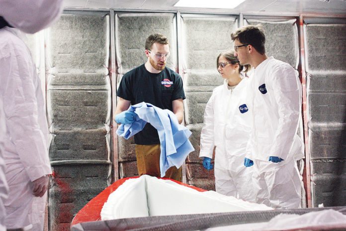 IYRS Shool of Technology and Trades student Andrew Leonard, black T-shirt, shows Massachusetts Institute of Technology students Carrie McKnelly and Tyler Crain how to prepare a mold for a lightweight canoe. The project was one of several laminating exercises MIT students participated in from Jan. 15-17 during a seminar on composites technology at IYRS’ Bristol campus. Students used the exercises to create structures of composite canoes and cylindrical beams. / COURTESY MICHAEL CAMERON