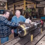 BLUEPRINT FOR SUCCESS: Bruce Sandberg, left, and his father, Sandberg Machine and Engineering owner Bob Sandberg, look over blueprints. The shop, which has 20 employees, handles projects for about 30 companies in Rhode Island. / PBN PHOTO/MICHAEL SALERNO