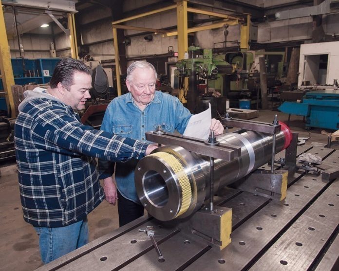 BLUEPRINT FOR SUCCESS: Bruce Sandberg, left, and his father, Sandberg Machine and Engineering owner Bob Sandberg, look over blueprints. The shop, which has 20 employees, handles projects for about 30 companies in Rhode Island. / PBN PHOTO/MICHAEL SALERNO