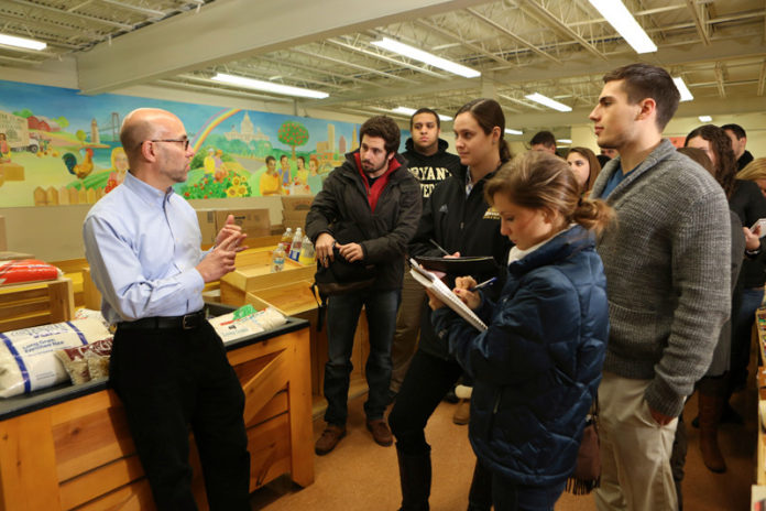 LEARNING THE ROPES: Rhode Island Community Food Bank CEO Andrew Schiff, left, explains his organization’s operations to freshmen in Bryant’s experiential learning program: Innovation and Design Experience for All. / COURTESY PAT O’CONNOR