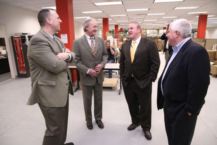 From left: Pawtucket Mayor Donald R. Grebien and Gov. Lincoln D. Chafee tour the Tunstall Americas facility at 100 Freight on Feb. 4 with Tunstall President and CEO Brad Waugh and Public Information Officer Glenn Morin. By the end of this month Tunstall says it will have exceeded a commitment to bring 250 jobs to Rhode Island, two months early. The company says it will have hired 269 workers by the end of February. / COURTESY CITY OF PAWTUCKET