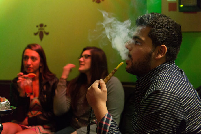 WHERE THERE’S SMOKE: Providence is cracking down on hookah lounges, but has yet to extinguish the practice. Pictured above, from left: patrons Devon Mills, Leanne Lamoly and Ghazy Daher at Skarr Hookah Lounge. / PBN PHOTO/RUPERT WHITELEY