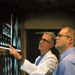 Is Ocean State a fit for ‘medical tourism’ model? LASER FOCUS: Already boasting locations in five states, Florida-based Laser Spine Institute is eyeing a potential location in Warwick. Above, Dr. Michael Weiss, left, consults with a Laser Spine Institute patient. / COURTESY LASER SPINE INSTITUTE
