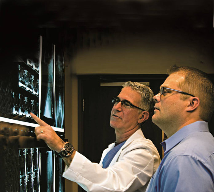 LASER FOCUS: Already boasting locations in five states, Florida-based Laser Spine Institute is eyeing a potential location in Warwick. Above, Dr. Michael Weiss, left, consults with a Laser Spine Institute patient. / COURTESY LASER SPINE INSTITUTE