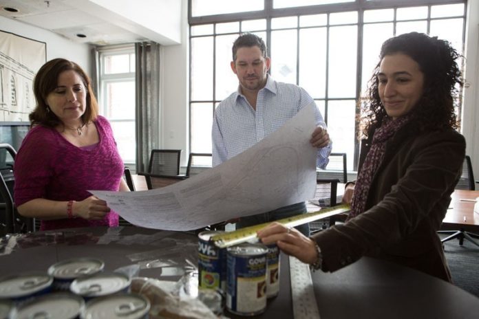 CAN-DO SPIRIT: From left, Carmen Warner, Michael Dowhan and team captain Andrea Torizzo discuss plans for their Canstruction project at Northeast Collaborative Architects’ Providence office. / PBN PHOTO/RUPERT WHITELEY