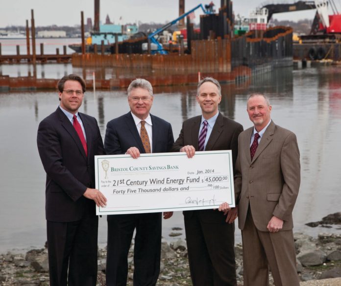 BRISTOL COUNTY SAVINGS BANK is investing $45,000 in the New Bedford Wind Energy Center at the Port of New Bedford. Attending the passing of the ceremonial check are, from left, Matthew Morrissey, managing director of the New Bedford Wind Energy Center, Bristol County Savings Bank President and CEO Patrick J. Murray Jr., New Bedford Mayor Jon F. Mitchell, and Bristol County Savings Bank Senior Vice President for Commercial Lending Pete Selley. / PHOTO COURTESY BOB BARTLETT
