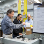LEAN AND LIKING IT: igus&rsquo; adoption of lean practices has helped the company expand while maintaining a calm and smooth-running operation, according to company executives. Going over a company order are, from left, Vice President Richard Abbate, assembly tech William Solorzano and Warehouse Operations Manager Gerry Fournier. / PBN PHOTO/RUPERT WHITELEY