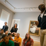 BANK OF AMERICA RHODE ISLAND PRESIDENT Bill Hatfield, rear, watches as students from George J. West Elementary School in Providence on a field trip this past Tuesday listen to an educator at the Rhode Island School of Design Museum of Art. Lt. Gov. Elizabeth Roberts sits beside him. The bank has provided a $10,000 grant for a Big Yellow School Bus program offered by The Rhode Island State Council on the Arts. / COURTESY  REINHARD SOKOL