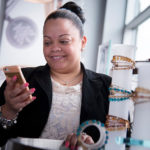 Geo-location technology linking stores, shoppers CROWN JEWEL: Alex & Ani employee Keisy Marcano checks messages on her smart-phone at the retail store in Cranston. The company has adopted new sensor technology called the iBeacon that allows stores to detect, send messages and interact with customer mobile phones when they are in or near the store. / PBN PHOTO/MICHAEL SALERNO