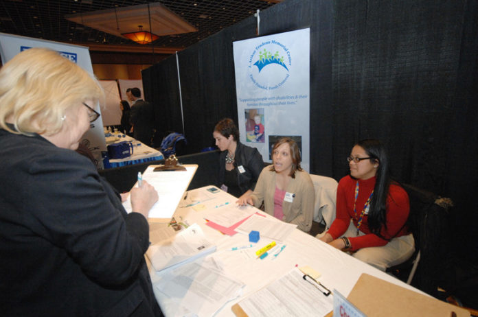 Gail Simon, left, fills out a job application for the J. Arthur Trudeau Memorial Center in Warwick, at the Ocean State Small Business Expo & Career Development Fair on March 30. The event was held at the Twin River Event Center in Lincoln. Sponsored by JobsInRI.com, the annual expo attracts small and medium-sized businesses. The event focuses on businesses making connections with each other. The career-development component is designed to help employers such as the Trudeau center find skilled workers. / PBN PHOTO/BRIAN MCDONALD
