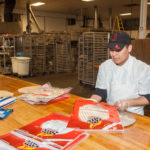 EATING WELL: Founded in 2009, Providence-based Top This! Fire-Grilled Pizza Crusts produces about 3,000 crusts, or 125 cases a day. Above, company employee Pablo Tum at work. / PBN PHOTO/TRACY JENKINS