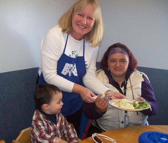 LENDING A HELPING HAND: Lynne Kelly, center, community relations manager at Collette, offers Patricia Pennuchi and her son Joseph a hot lunch during the company’s day of service at the McAuley House.