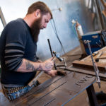 Steel Yard eyes funding balance ALONG FOR THE RIDE: Tim Ferland works on bicycle racks for Johnson & Wales University. Ferland is the part-production manager at the Steel Yard, which is seeking new revenue sources to sustain its expansion. / PBN PHOTO/MICHAEL SALERNO