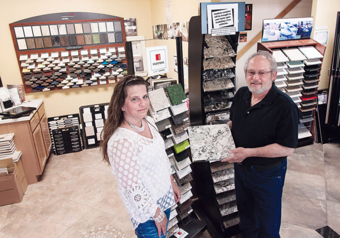 Assistant Manager Susan Wilson and Richard Guglielmo, owner of Tile Craft Design Center in South Kingstown, in the showroom. Guglielmo is holding a sample of Cambria natural stone. The company, founded in 1960, sells and installs tile, countertops and flooring. “We handle jobs from start to finish,” Guglielmo said. “Customers deal with one person and that’s me.” / PBN PHOTO/MICHAEL SALERNO