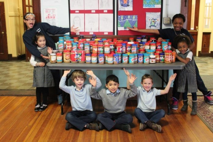 WASHINGTON TRUST'S 14th annual peanut butter drive collected more than five tons of peanut butter from 15 businesses and 16 schools across the state for local food pantries. Above, students at Saint Paul School in Cranston pose with their collections. / COURTESY SAINT PAUL SCHOOL