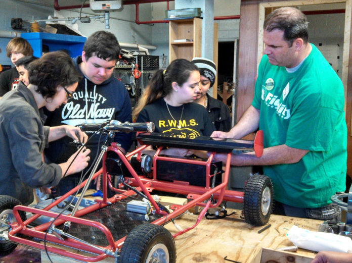 SCOTT GEYER, right, of Warwick works with students from Roger Williams Middle School and members of Boys & Girls Clubs of Providence to build a solar-electric go-kart on Fidelity Cares Day.