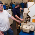 Knowledge transfer key to growth HIS TURN: NEIT student and Swissline Precision Manufacturing intern Bill Johnson, left, works with Gerard Hester, a certified machine operator. / PBN PHOTO/MICHAEL SALERNO