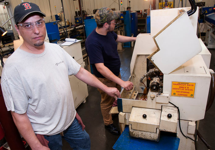HIS TURN: NEIT student and Swissline Precision Manufacturing intern Bill Johnson, left, works with Gerard Hester, a certified machine operator. / PBN PHOTO/MICHAEL SALERNO
