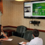 Video expands face-to-face meetings WORD TRAVELS: In a conference room at Savings Institute Bank & Trust in Newport, Cristina Feden and Tom Olivier videoconference with Jason White, IT director at the institution’s training center in North Windham, Conn. / PBN PHOTO/KATE WHITNEY LUCEY