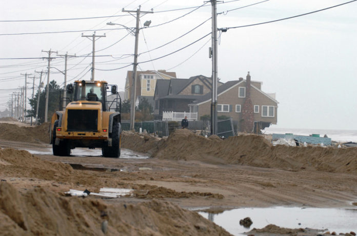 FEDERAL SCIENTISTS WITH the U.S. Bureau of Ocean Management will collaborate with the University of Rhode Island and the R.I. Coastal Resources Management Council to survey offshore sand resources that could be used to prevent future coastal erosion. Above, a machine clears sand off Atlantic Ave. in Westerly after Hurricane Sandy. / PBN FILE PHOTO/BRIAN MCDONALD