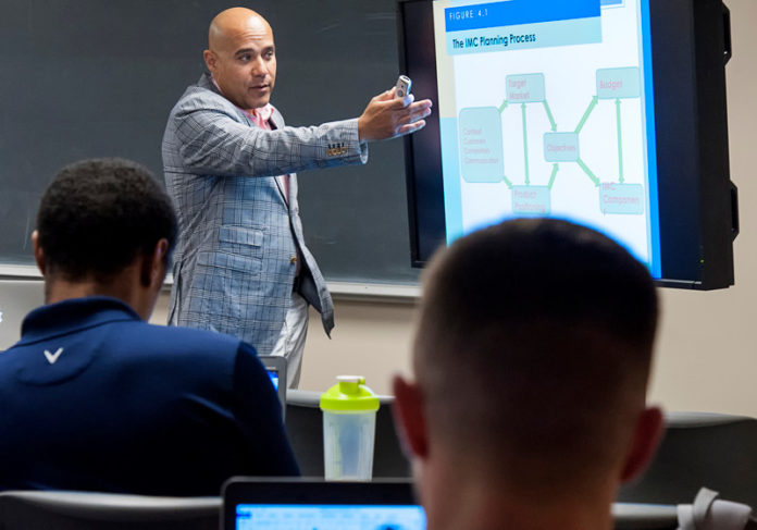 COURSE WORK: URI College of Business Administration doctoral student Gerry Matos teaches a class at the school’s Providence campus. The program is celebrating its 90th anniversary. / PBN PHOTO/ MICHAEL SALERNO