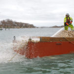UNCHARTED WATERS: A contractor from East Coast Construction uses a high-pressure hose to deploy oyster shells in Quonochontaug Pond for a project spearheaded by The Nature Conservancy. The oyster shells are from Newport Harbor Corp.’s restaurants and Matunuck Oyster Bar, which are collaborating with the group. / COURTESY THE NATURE CONSERVANCY