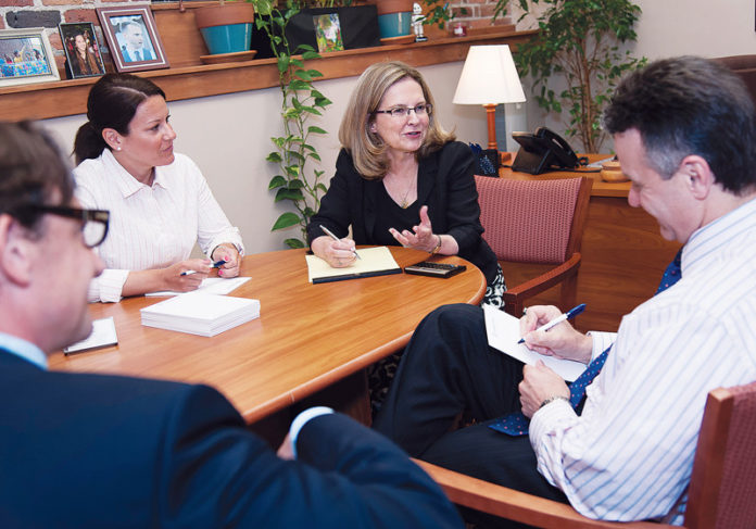 DIRECT CONTACT: StrategicPoint Managing Director and Chief Investment Officer Betsy A. Purinton, pictured above in black top, speaks with, from left, financial advisers Sean Giles and Chrissy Canapari and Managing Director and Chief Compliance Officer Richard Anzelone. / PBN PHOTO/MICHAEL SALERNO