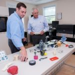 FASTER AND CHEAPER: With the growing embrace of 3-D printing in the manufacturing and academic worlds, R&D Technologies is experiencing strong growth. Here Justin and Andrew Coutu, president and CEO of the company respectively, show off many objects produced with the technology. / PBN PHOTO/MICHAEL SALERNO
