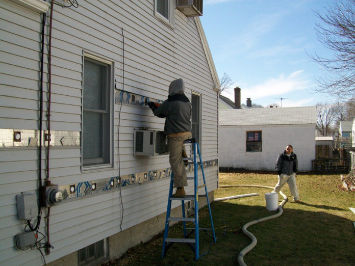 HEATING UP: More than 2,100 Rhode Island homeowners have taken advantage of National Grid’s Heat Loan Program, which offers zero-interest loans to residential property owners for qualifying energy-efficiency improvements. Above, insulation is blown into the walls of a house. / COURTESY NATIONAL GRID