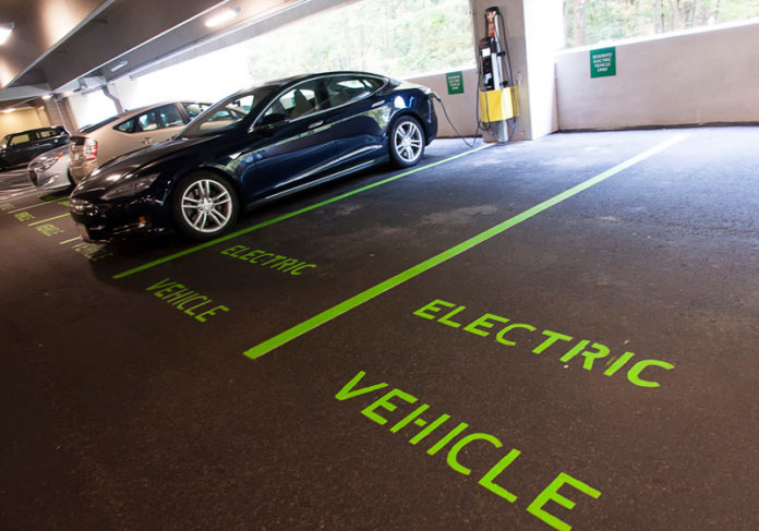 STAYING CURRENT: Several companies, including Fidelity Investments, are implementing electric-vehicle charging stations for their employees. Above, a car charges in the company’s parking garage at 900 Salem St. in Smithfield. / PBN PHOTO/MICHAEL SALERNO