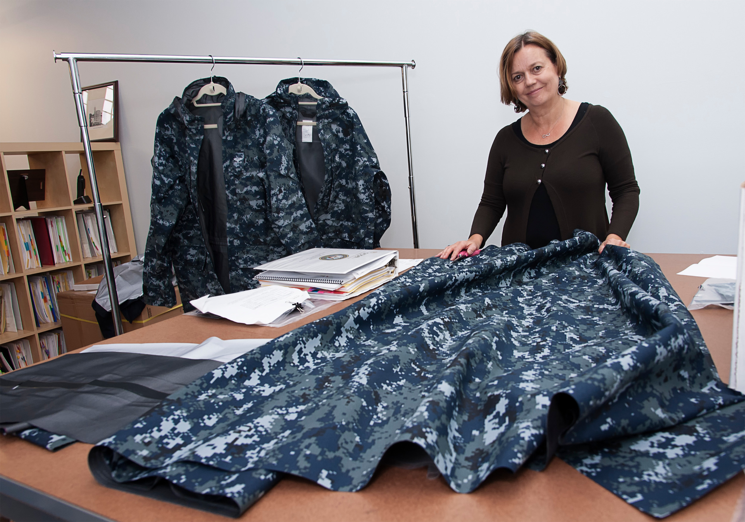 READY FOR BATTLE: Clare King, president of Propel LLC, handling the material used to make one of the coats they are producing for the US Navy. The coats are produced with limited thread and needle, instead using bonding and welding techniques. / PBN PHOTO/ MICHAEL SALERNO