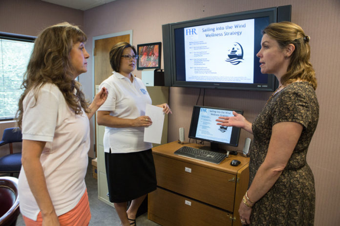 PBN PHOTO/RUPERT WHITELEY
THE FULL PICTURE: Fellowship Health Resources has created a wellness program that supports the physical, mental and spiritual needs of its staff, including a new creative self-expression program modeled on what the mental health agency provides its clients. Engaged with the company wellness portal are, from left, Human Resources Director Karen Trudeau, Benefits Administrator Jennifer McKenna and President and CEO Debra M. Paul.