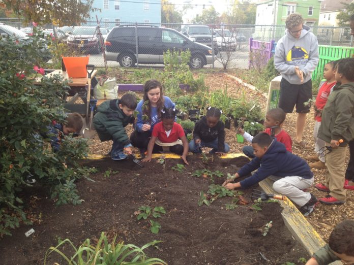 BROWN UNIVERSITY undergraduate Mara Quinn, center, works with teachers and students in an outdoor garden at Fortes Elementary School in Providence. / COURTESY BROWN UNIVERSITY