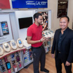 WELL CONNECTED: Ray Leung is president of CRMS Inc., which owns 12 Wireless Zone stores, including four in Rhode Island. At right is Leung, at the Taunton Ave. Wireless Zone store in East Providence, with store manager Brad Lavoie. / PBN PHOTO/ MICHAEL SALERNO