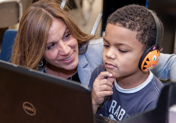 FREE DESIGN: Asa Messer Elementary School has been integrating technology with traditional classroom elements. Above, Leslie Tirocchi, a teacher at Asa Messer Elementary, works with Joel Valdez, age 6. / PBN PHOTO/MICHAEL SALERNO
