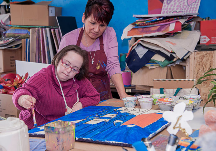 SUPPORTING ROLE: Roxanne Nadeau, left, works on a painting at Access Point Rhode Island with direct-support professional Karen Matteson. Through CCRI, APRI has offered two different, for-credit courses in a professional training program. / PBN PHOTO/MICHAEL SALERNO